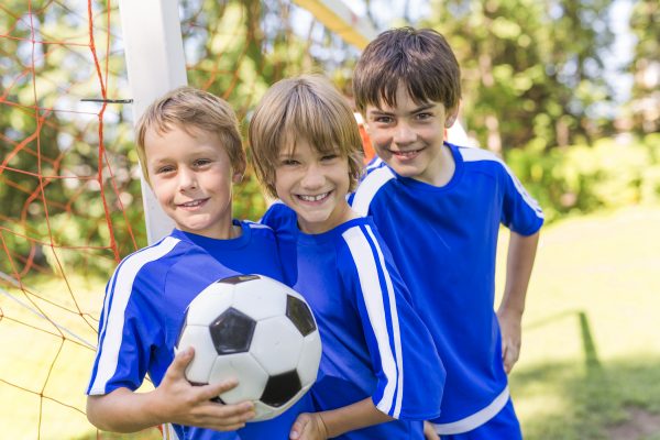 three nice Young boys with soccer ball on a sport uniform